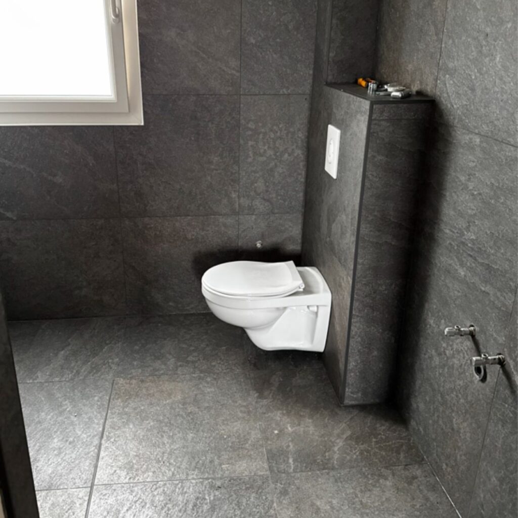 WC suspendu dans salle de bain avec carrelage gris foncé